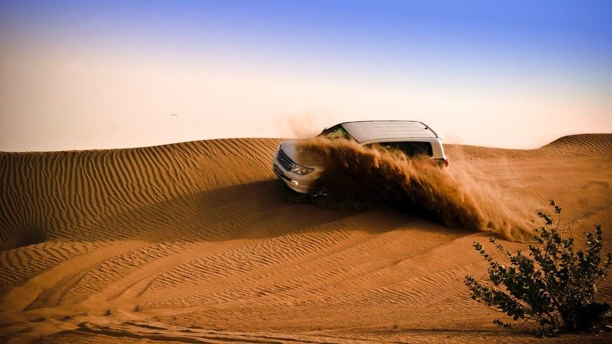 Auto rijdt door zandduinen