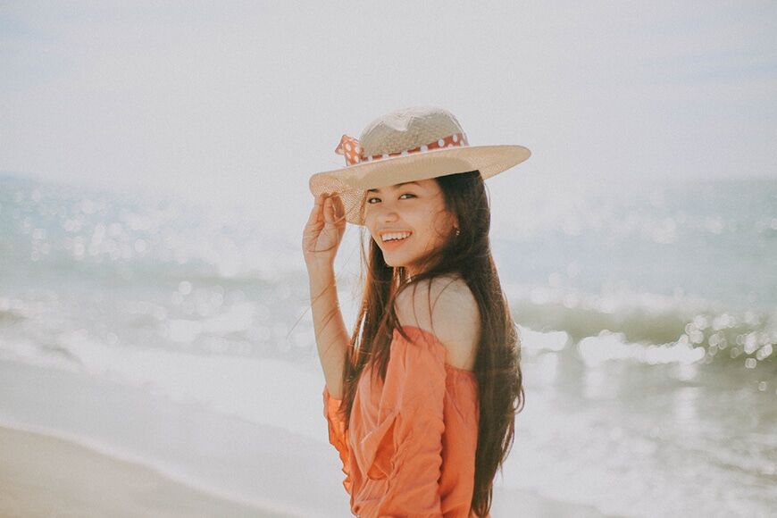 Meisje met hoed op strand met wazige backbround