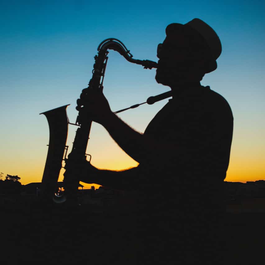 Het silhouet van de saxofonist tegen de zonsondergang