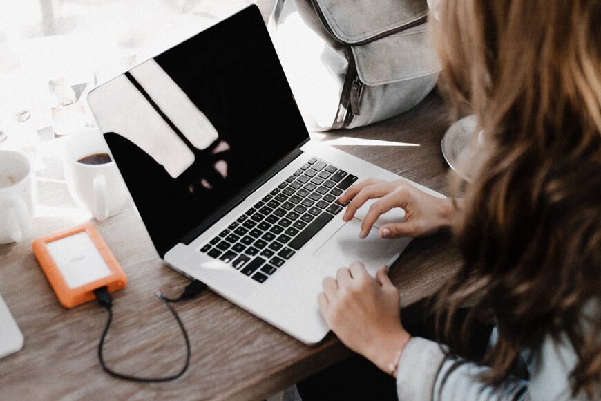 Vrouw zittend op laptop computer met externe schijf