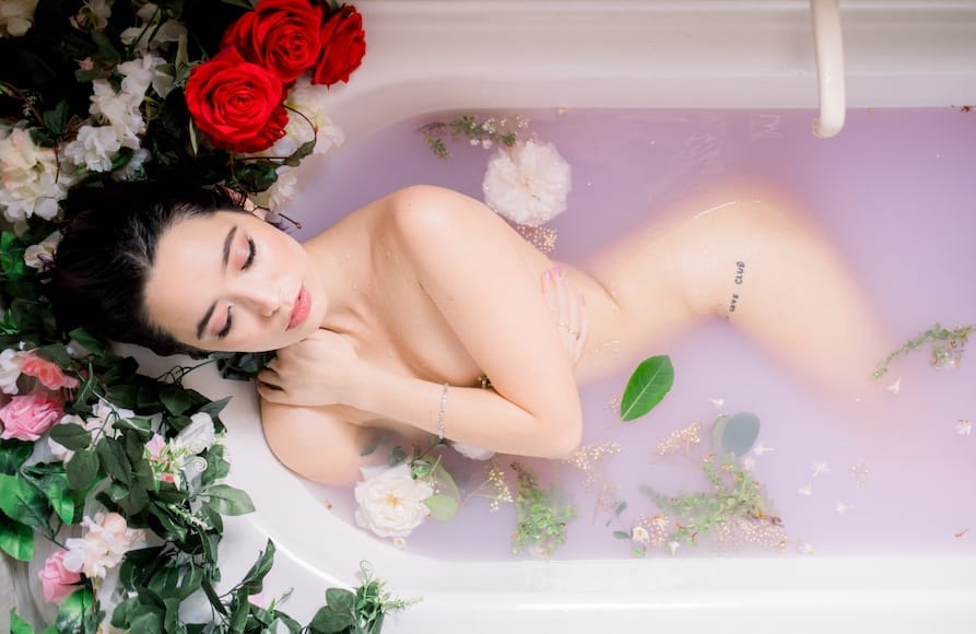 Vrouwelijk model in melkbad met bloemen