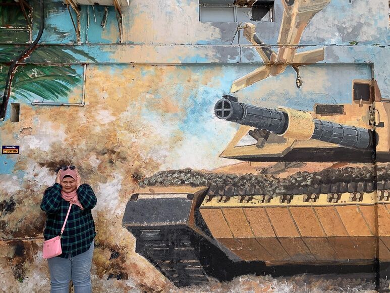 Meisje bedekkende oren naast street art van een tank