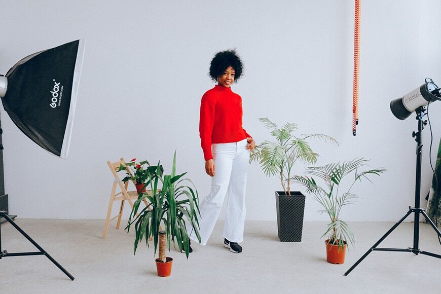 Vrouw die poseert in een studio met planten en verlichtingsapparatuur