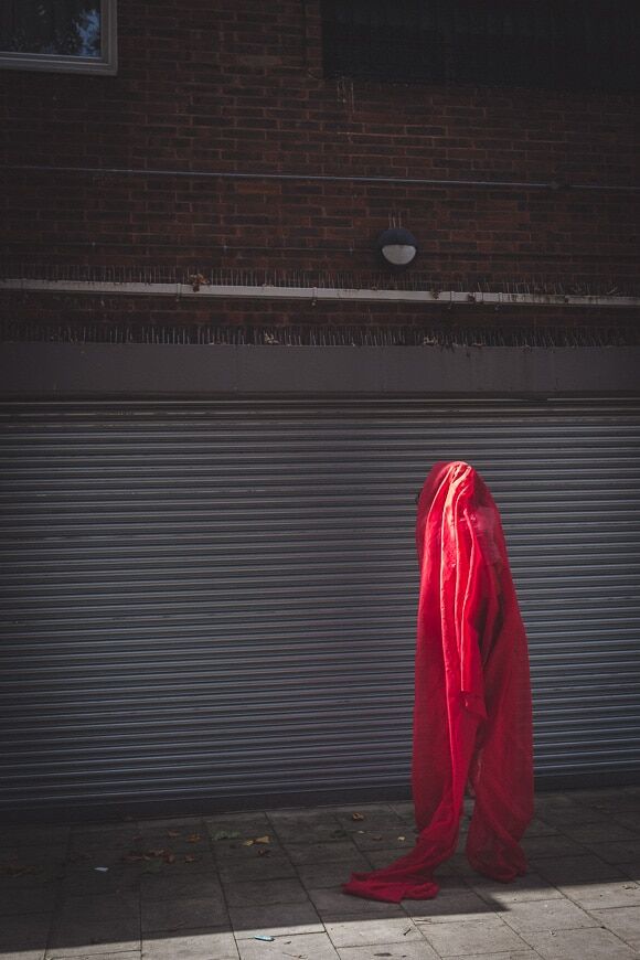 Conceptuele foto van persoon gesluierd in rode stof