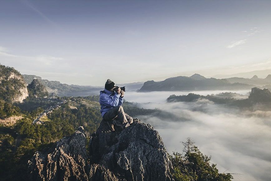 Fotograaf zittend op rotsachtige rots