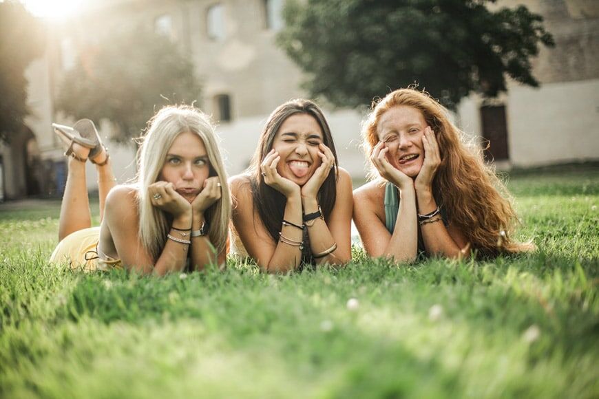 Drie meisjes die poseren op gras en grappige gezichten maken