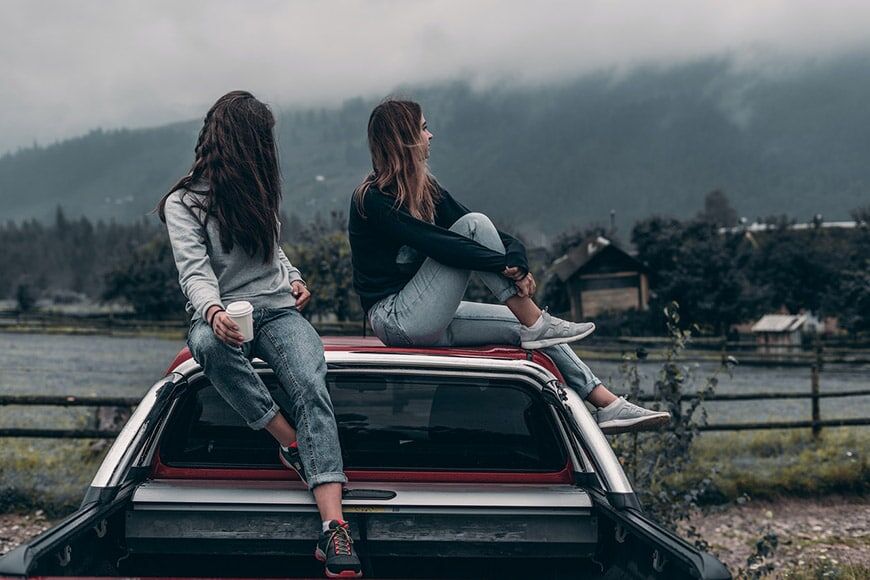 Twee meisjes die bovenop een auto zitten
