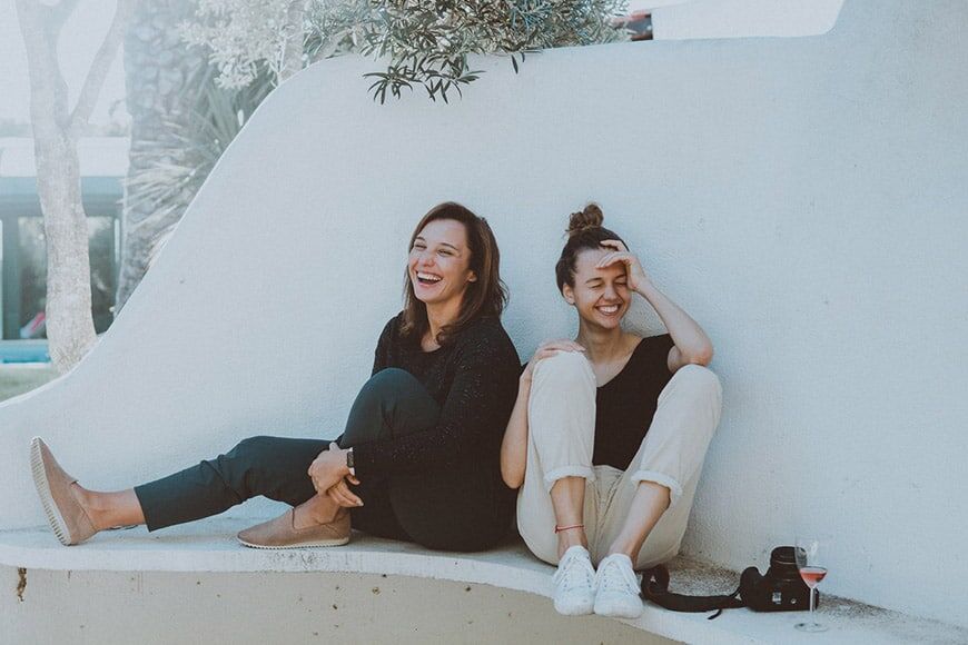 Foto van twee vriendinnen die zitten en lachen