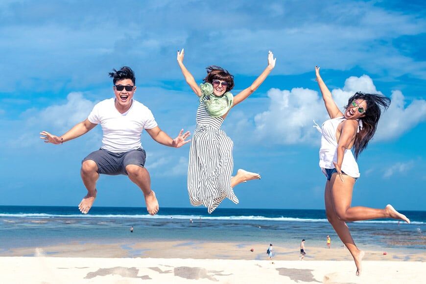 Drie vrienden springen in de lucht op het strand
