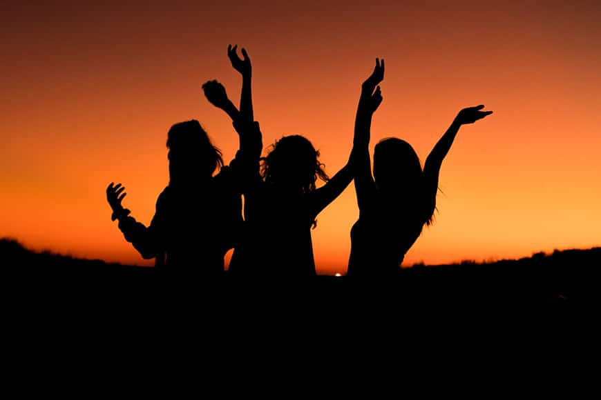 Silhouet van drie vrouwen met armen in de lucht