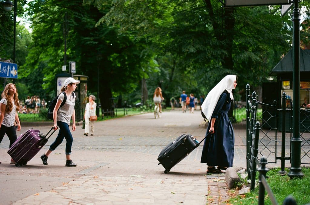 Stadsfotografie - mensen met koffers die door een park lopen