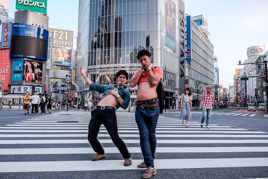 Een drukke Japanse stad met twee jonge mannen die poseren op een zebrapad