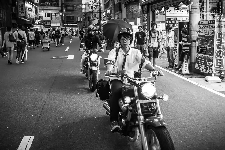 Zwart-witfoto van een drukke Japanse straat met een man op een motor