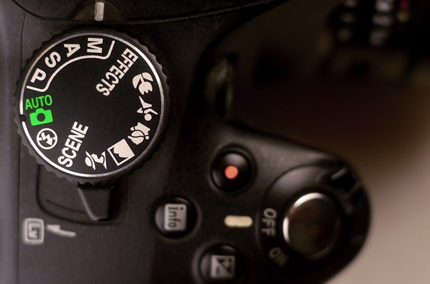 Close-up macro opname van een moderne digitale SLR camera. Gedetailleerde foto van zwarte camerabehuizing met knoppen om de opnamemodi te bedienen en te schakelen