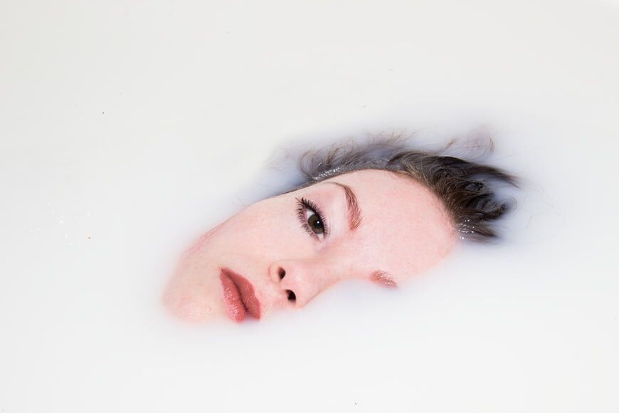 Modellen gezicht ondergedompeld in melkbad met een eenvoudige samenstelling