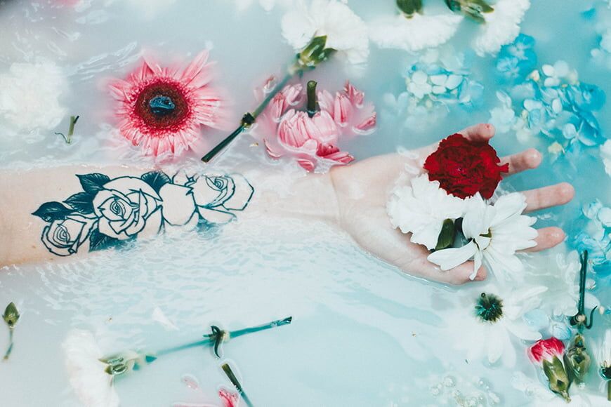 Melkbad fotografie ideeën - zwevende arm in een melkbad met bloemen