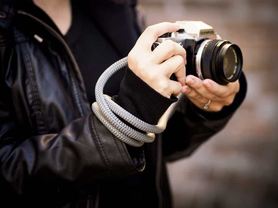 Een fotograaf wikkelt haar touwband om haar hand om haar camera vast te zetten.