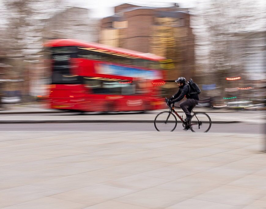 Man op een fiets met rode bus wazig op de achtergrond